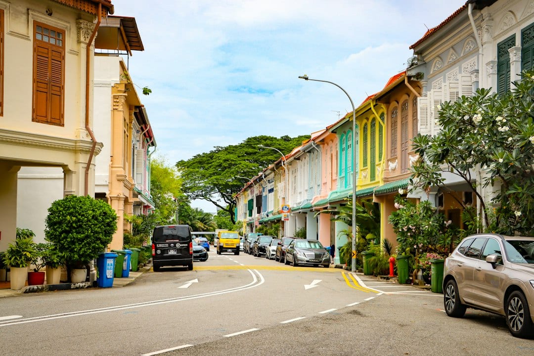 Colourful shophouses lining a street with parked cars